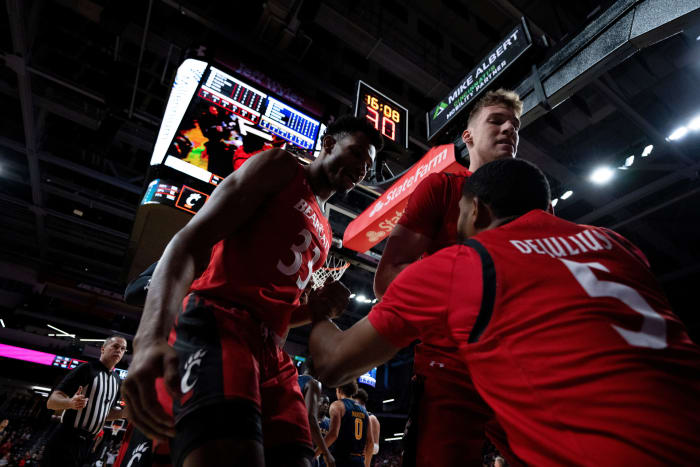 Cincinnati Bearcats forward Ody Oguama (33) and Cincinnati Bearcats forward Viktor Lakhin (30) help up Cincinnati Bearcats guard David DeJulius (5) after he was fouled while shooting in the first half of the NCAA men s basketball game between the Cincinnati Bearcats and the La Salle Explorers at Fifth Third Arena in Cincinnati on Saturday, Dec. 17, 2022. Ncaa Basketball La Salle Explorers At Cincinnati Bearcats Ac